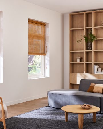 Bruinhouten Woodweave blinds in een landelijke woonkamer met grijsblauwe bank en een houten kast